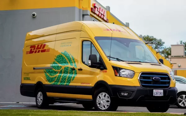 Autoutilitară galbenă DHL în fața unui centru de curierat